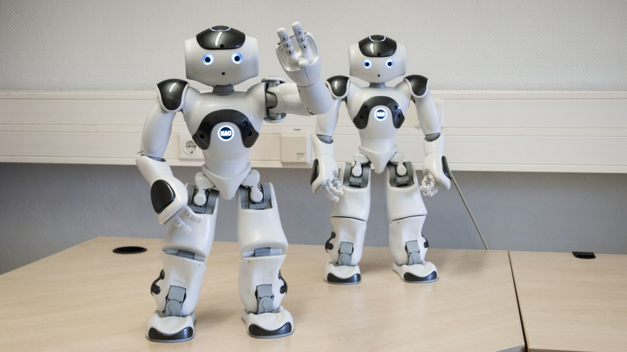 Picture of two Nao robots. One is waving
