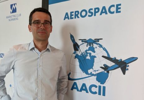 Philipp Beckerle in front of a poster with the logo of the AACII