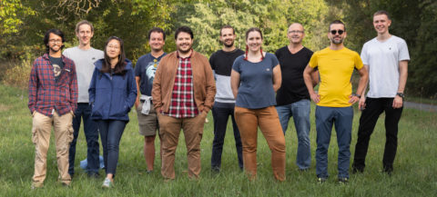 The members of the research group can be seen standing in a green field.